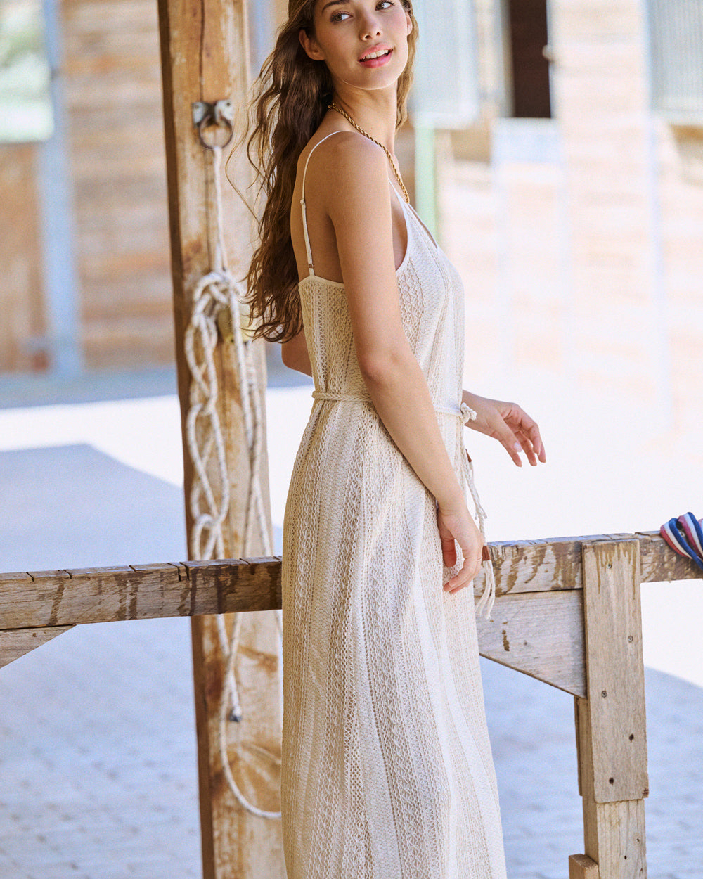 Robe longue en crochet beige à bretelles avec cordon en ceinture, vue de profil.